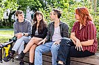 Foto von Studierenden die gemeinsam draußen auf der Bank sitze