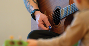Campus-Kita-Foto: Erzieher*in spielt Guitarre, Kind auch