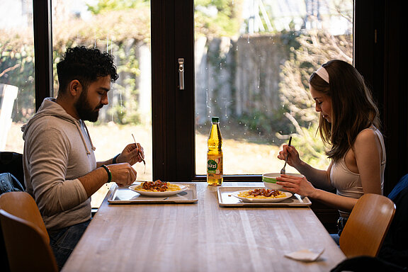 2 persons sitting & eating at a table of Zentralmensa