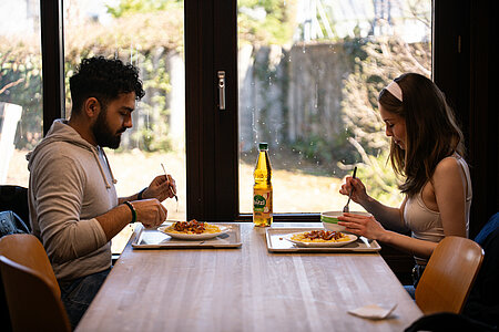 2 persons sitting & eating at a table of Zentralmensa