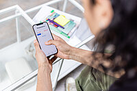 Photo taken over the shoulder of a person (student), showing the red numbers on the bank account in the app.